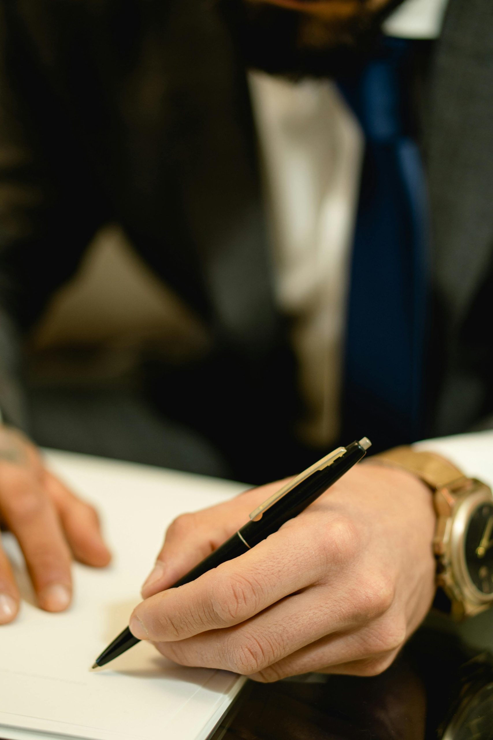 Close-up of hand writing in notebook using a blue pen, focus on creativity.